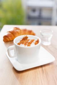 a cup of coffee on a plate with a pastry at Vila Ramona in Otopeni +18 photos