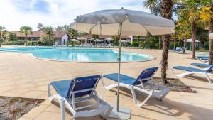 - deux chaises et un parasol en face de la piscine dans l'établissement Vacancéole - L'Allée des Dunes - Ondres Plage, à Ondres