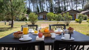 - une table noire avec un panier de pain et de jus d'orange dans l'établissement Vacancéole - L'Allée des Dunes - Ondres Plage, à Ondres
