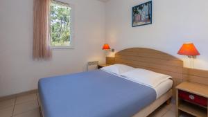 une chambre avec un lit bleu et une fenêtre dans l'établissement Vacancéole - L'Allée des Dunes - Ondres Plage, à Ondres 49 autres photos