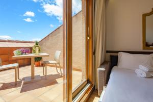 a bedroom with a balcony with a bed and a table at Hotel Exe Reina Isabel in Ávila