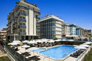 a resort with a swimming pool and umbrellas and a building at Hotel Byron Bellavista in Lido di Jesolo