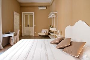sypialnia z dużym białym łóżkiem i krzesłem w obiekcie BluLassù City Center Rooms w Cagliari