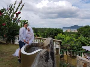 une mariée et un marié debout à côté d'une fontaine dans l'établissement Hibiscus House Seychelles Self Catering, à Victoria