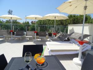 un patio con mesas, sillas y sombrillas en Hotel Villa Enea, en Cattolica