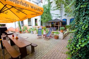 a patio with tables and chairs and an umbrella at Gästehaus Mezcalero in Dresden