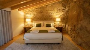 sypialnia z dużym łóżkiem w kamiennej ścianie w obiekcie Casas da Penha w mieście Penamacor