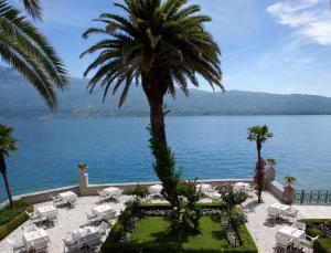 een resort met een palmboom en uitzicht op het water bij Hotel Villa Giulia in Gargnano