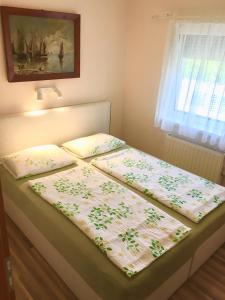 a bed with two pillows on top of it at Aranypart Apartman in Siófok