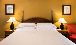 a large white bed with two lamps and a red chair at Occidental Caribe - All Inclusive in Punta Cana