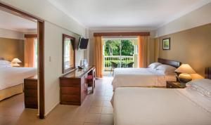 a hotel room with two beds and a television at Occidental Caribe - All Inclusive in Punta Cana