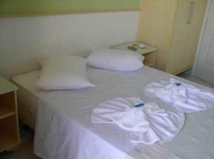 a bed with white sheets and pillows on top of it at Hotel Pousada Mineirinho in Balneário Praia do Leste