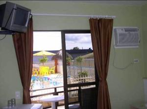 a television and a window in a room at Hotel Pousada Mineirinho in Balneário Praia do Leste