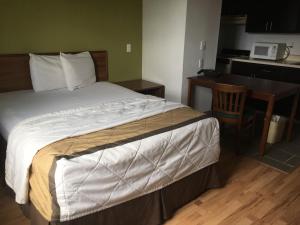 a bedroom with a bed and a table and a kitchen at Welcome Suites Hazelwood Extended Stay Hotel in Hazelwood