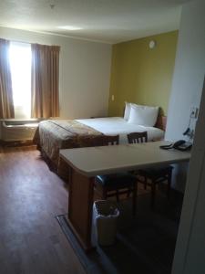 Habitación de hotel con cama, escritorio y mesa. en Welcome Suites Hazelwood Extended Stay Hotel en Hazelwood
