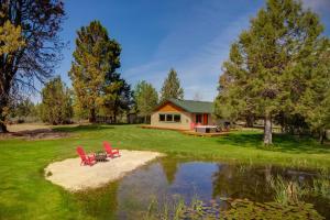 a house with two red chairs next to a pond at Apache Greens in Sisters