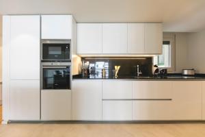 a white kitchen with white cabinets and appliances at Bravissimo La Rambla penthouse in Girona