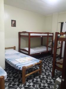 a room with two bunk beds and a checkered floor at Villa Travellers House in Moalboal