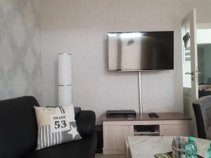 Una sala de estar con un sofá y un televisor en la pared. en Haus Skye, en Großenbrode