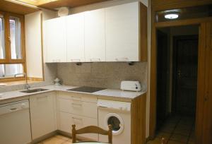 a kitchen with white cabinets and a washer in it at Apartmento AZKOITI in Ochagavía