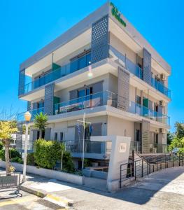 biały budynek z niebieskimi balkonami przy ulicy w obiekcie 7Palms w mieście Rodos