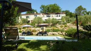 una casa con piscina e due sedie e ombrellone di Le Vallon des Oliviers a Montauroux