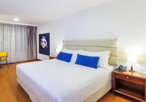 a bedroom with a large white bed with blue pillows at Pop Art Hotel Manizales Centro Histórico in Manizales