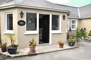 una casa blanca con plantas delante en Killilagh Accommodation, en Doolin