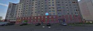 a large red building with cars parked in a parking lot at Apartment on Lunacharskogo in Tver