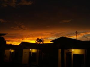 the sun is setting in the sky over the houses at Kalunai Hostel in Puerto Viejo