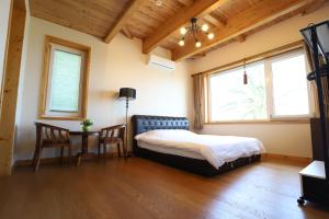 una camera da letto con un letto, un tavolo e finestre di Jeju Lake Pension a Jeju Altre 56 foto