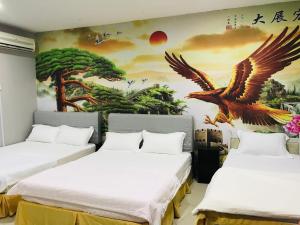 two beds in a room with a painting on the wall at Home Inn Hotel in Ipoh