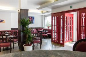 a restaurant with red doors and tables and chairs at Hotel Milano in Tione di Trento