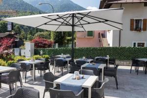 un restaurante con mesas, sillas y sombrilla en Hotel Milano, en Tione di Trento