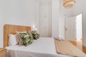 1 dormitorio blanco con 1 cama grande con almohadas verdes en Del parque flats letran, en Málaga