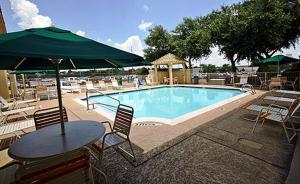 a swimming pool with a table and chairs and a table and umbrella at Motel 6-Garland, TX - Northeast Dallas in Garland