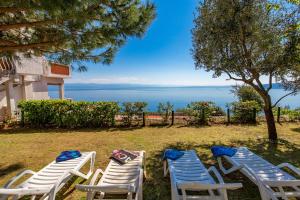 un groupe de chaises assises dans l'herbe avec l'océan dans l'établissement Apartments Davor, à Mošćenička Draga