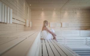 une femme assise sur un banc dans un sauna dans l'établissement Hirben Naturlaub, à Villabassa