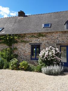 a brick house with flowers in front of it at La petite grange, La vieille ferme in Ruffiac