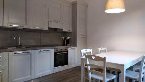 a kitchen with white cabinets and a white table and chairs at Casa Lin in Celle Ligure