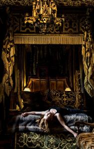 
a woman laying on a bed in a room at The Witchery by the Castle in Edinburgh
