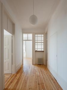 ein leeres Zimmer mit Holzboden und weißen Wänden in der Unterkunft Rua Tenente Campos Rego, Ground Floor in Coimbra