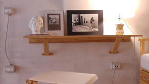 a shelf on a wall with a bust and pictures at BORGO PETELIA, Casa Chiarotti, Antica casa con scala esterna in Strongoli