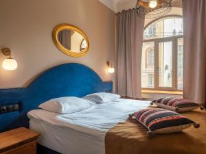 a bedroom with a bed with a blue headboard and a mirror at Greenwich by Friends in Saint Petersburg