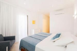 a white bedroom with a bed and a chair at OH LA LIFE! MAGNOLIA GOLF SUSANA in Adeje