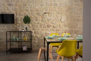 a dining room with a table and yellow chairs at Funduq ospitalità iblea in Pozzallo