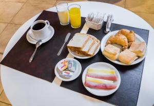 una mesa con platos de comida y tazas de café en Boer Hotel By Kube en Deán Funes