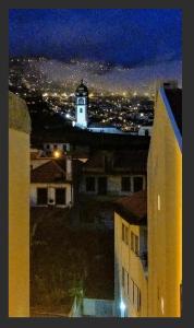 een uitzicht op een gebouw met 's nachts een klokkentoren bij Peaceful Top Floor Apt W Balconies - Cambridge RIGHT - AC in Funchal