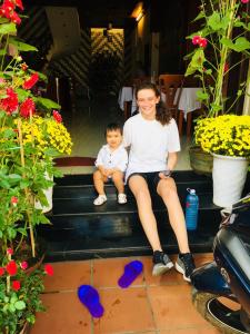 a woman and a child sitting on the stairs with flowers at Hoa Mau Don Homestay in Hoi An