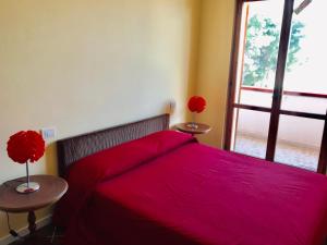a bedroom with a bed with a red bedspread and a window at Rodi Garganico in Foce Varano